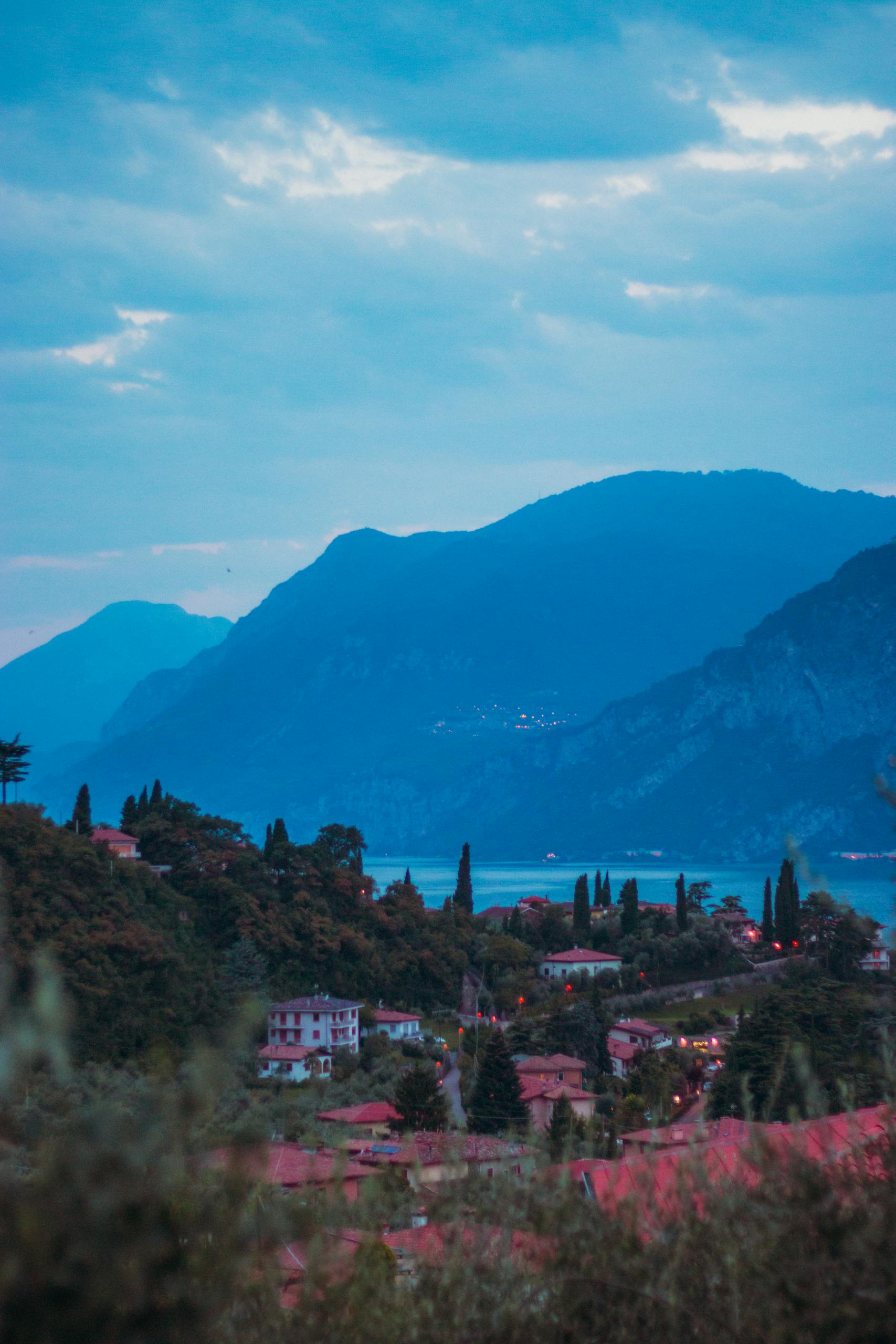 A beautiful panoramic view of Malcesine with Lake Garda and surrounding mountains at twilight.