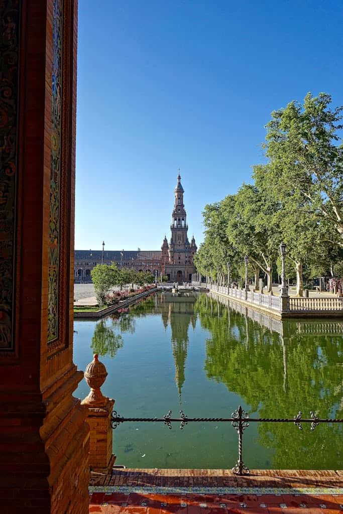 Historic Plaza de España in Seville featuring water reflections and classic architecture.