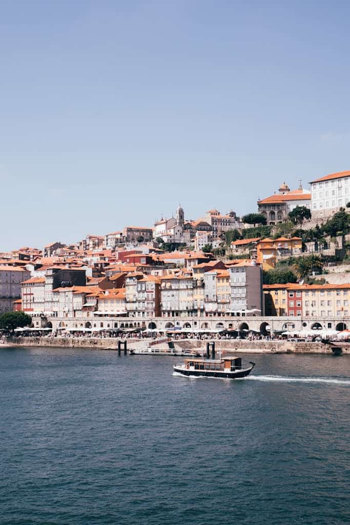 Charming view of Porto's Ribeira district and Douro River with a scenic boat under a clear sky.