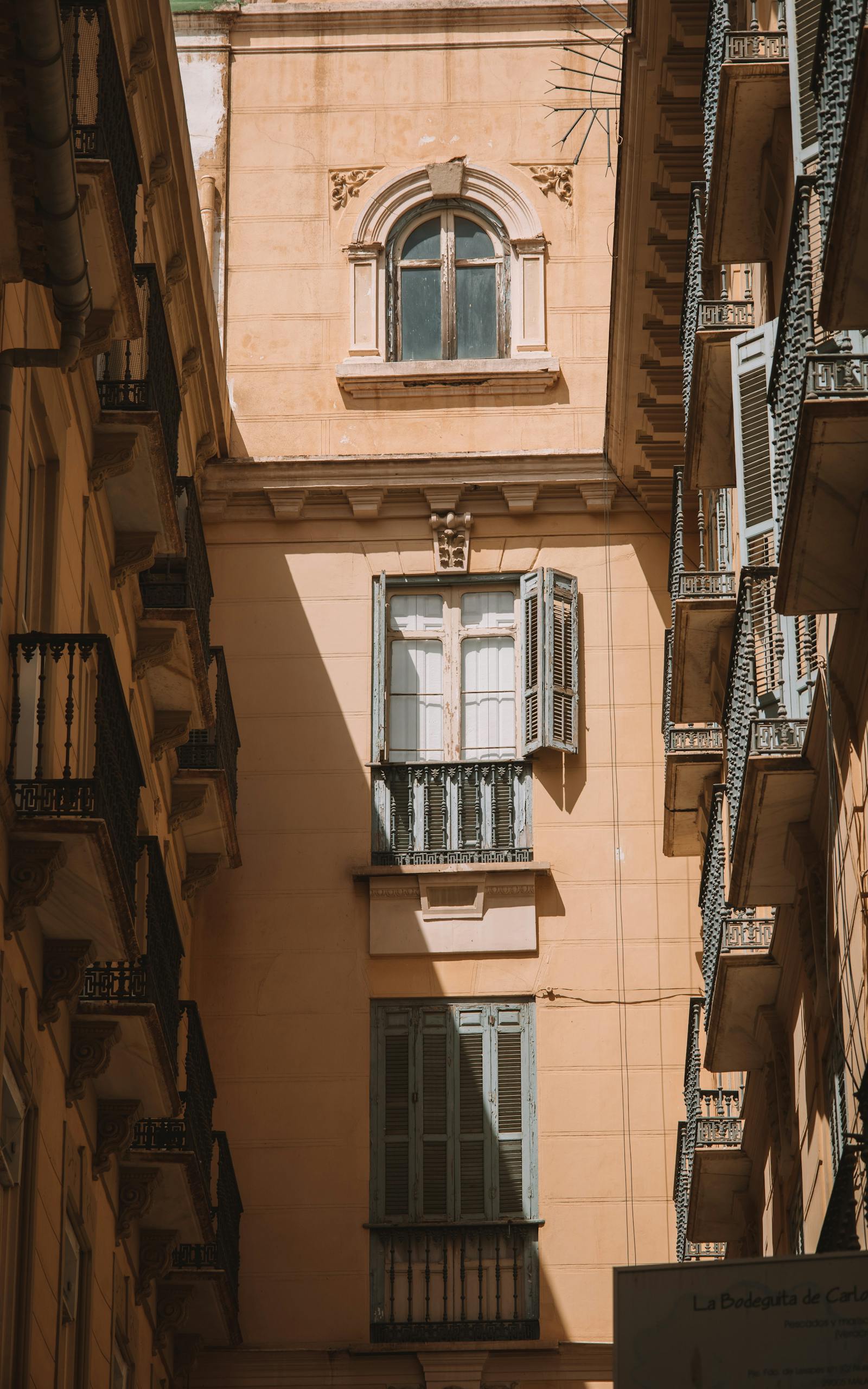Elegant low angle view of sunlit buildings in Málaga, Spain, showcasing classic architecture.