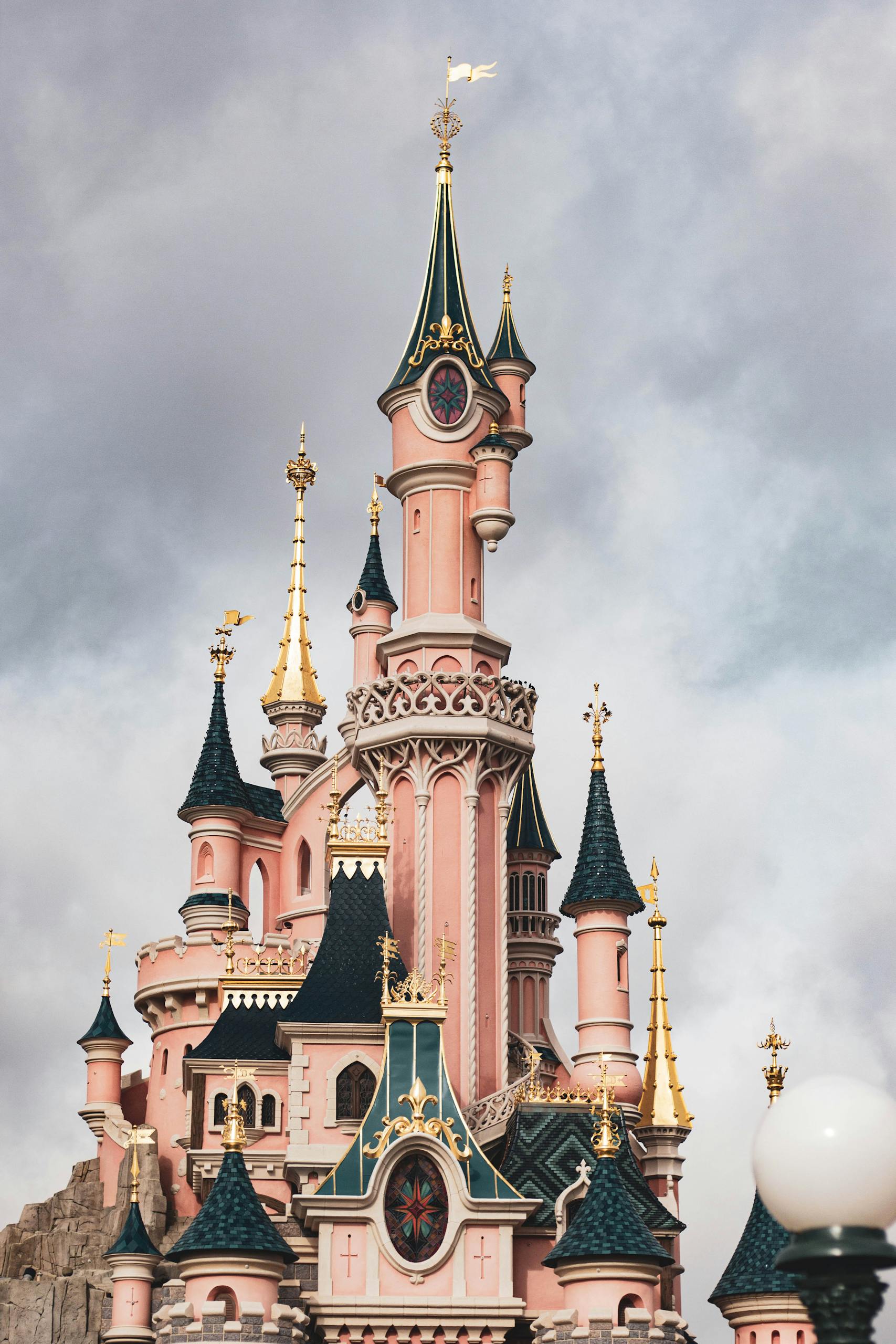 Elegant view of the iconic Sleeping Beauty Castle at Disneyland Paris with a moody sky.