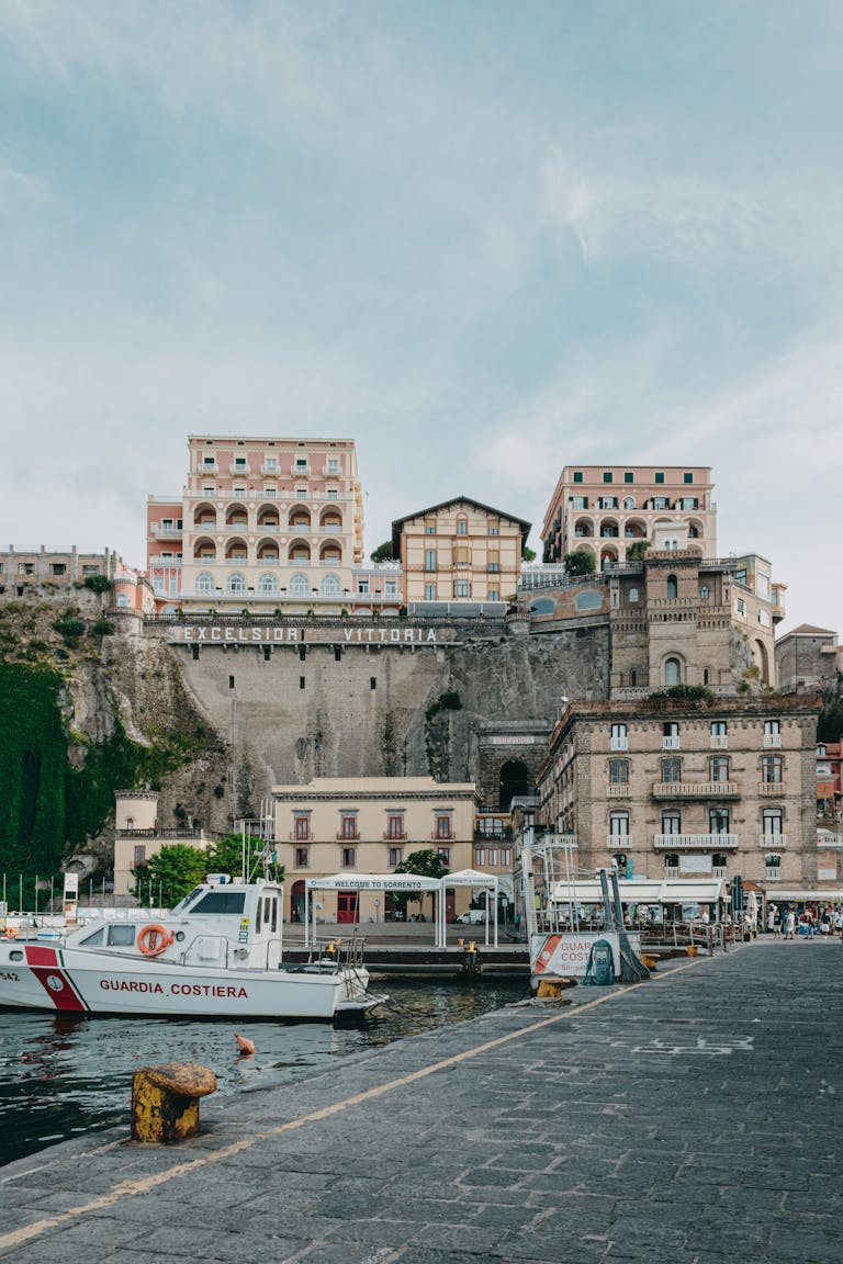 Picturesque Sorrento coastline with boats and historic Excelsior Vittoria Hotel.