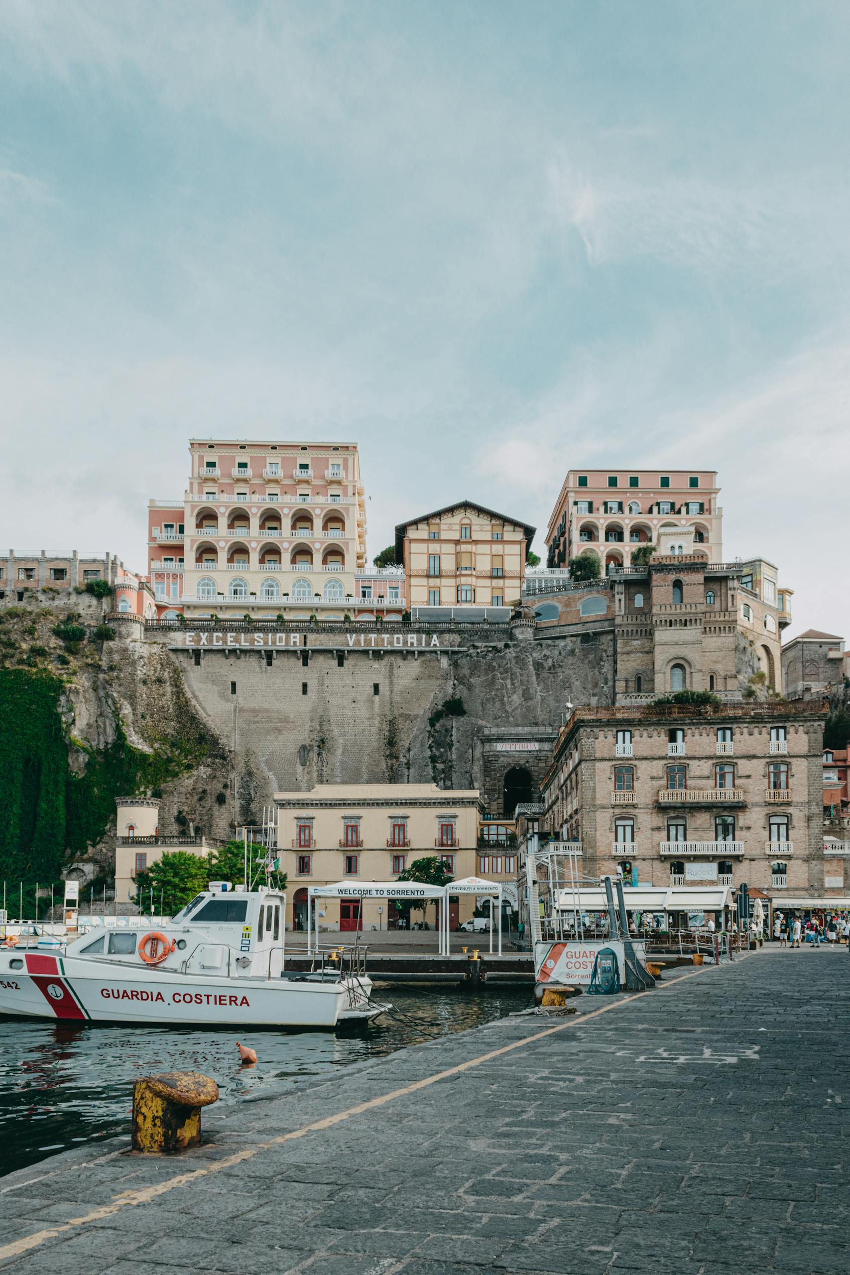 Picturesque Sorrento coastline with boats and historic Excelsior Vittoria Hotel.