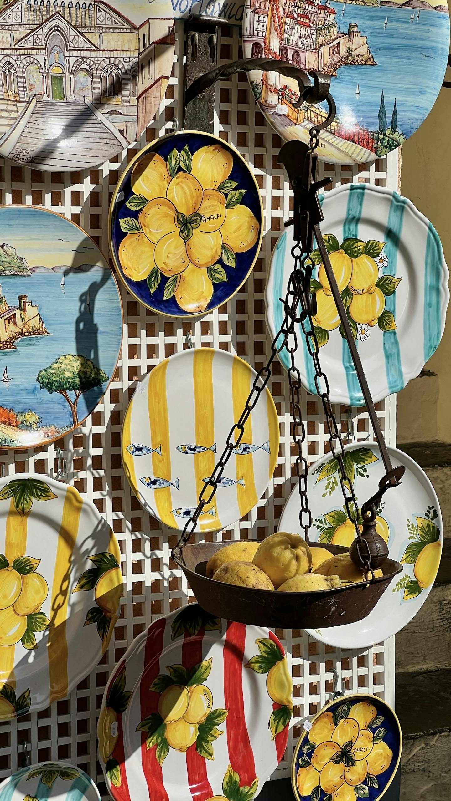 Vibrant hand-painted ceramic dishes with lemon motifs in a souvenir shop in Amalfi, Italy.