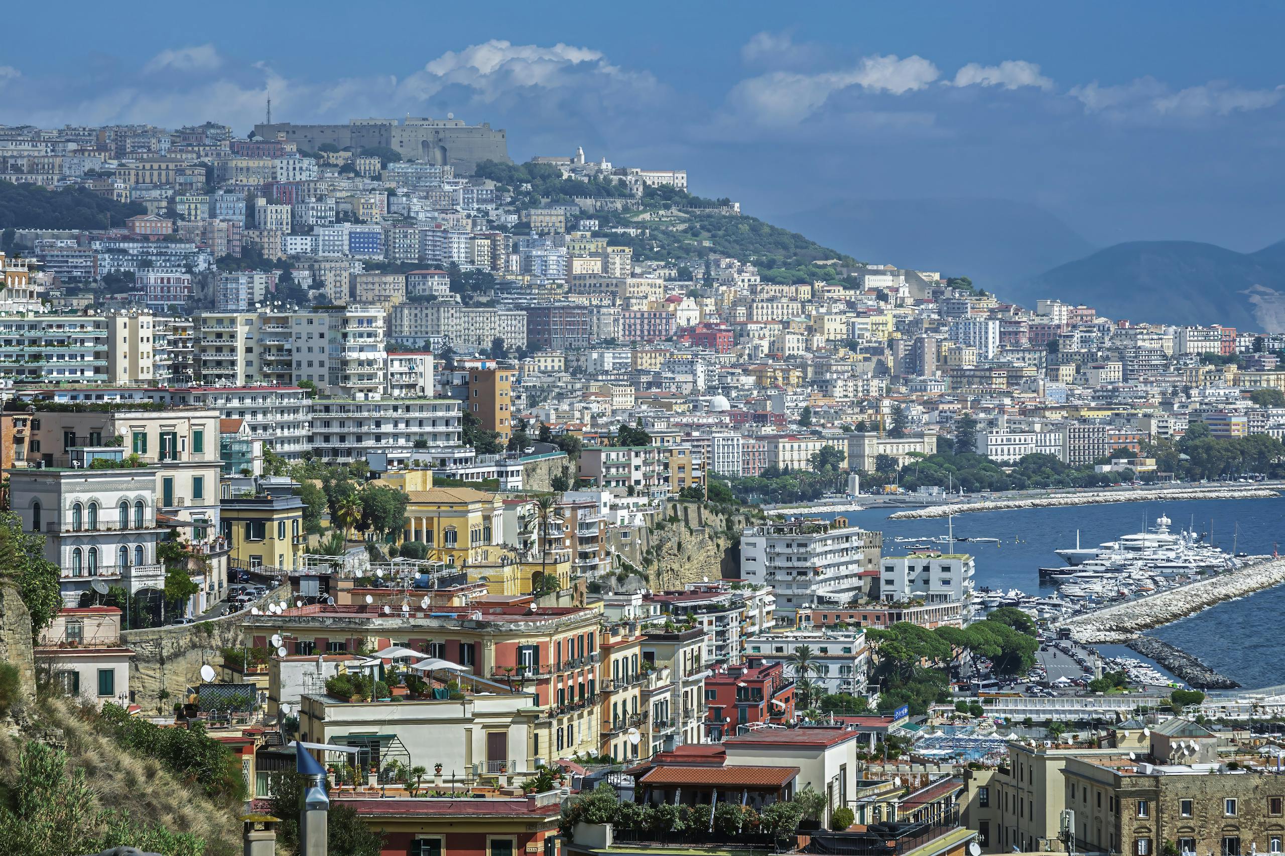A breathtaking view of the colorful buildings and coastline of Naples, Italy, showcasing the vibrant city life and stunning sea.