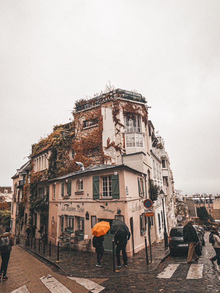 Captivating image of a rainy street in Montmartre, Paris, showcasing vintage architecture and pedestrians with umbrellas.