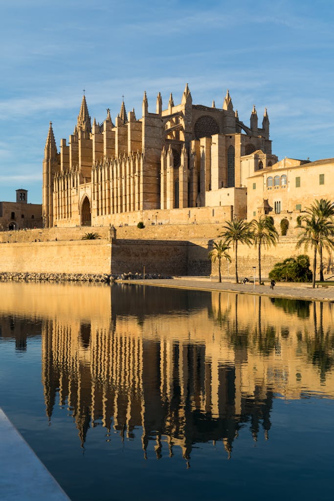Beautiful reflection of Palma de Mallorca Cathedral on calm water, showcasing gothic architecture.