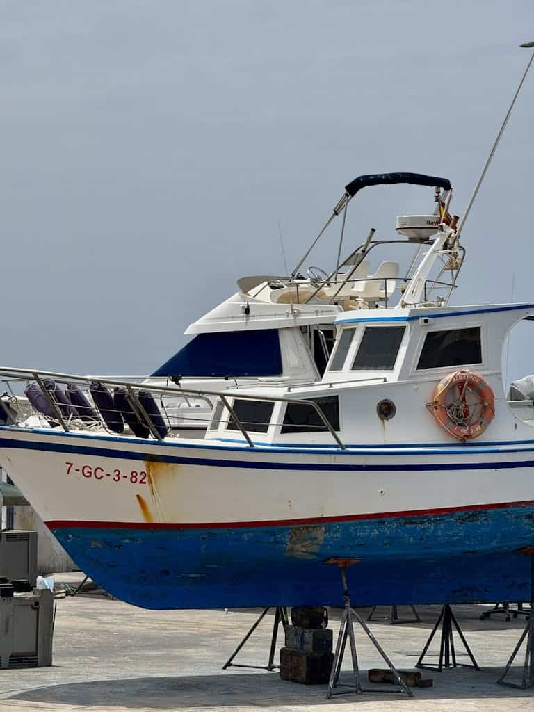 Colorful fishing boat docked at a harbor in Lanzarote, Spain under a clear sky.