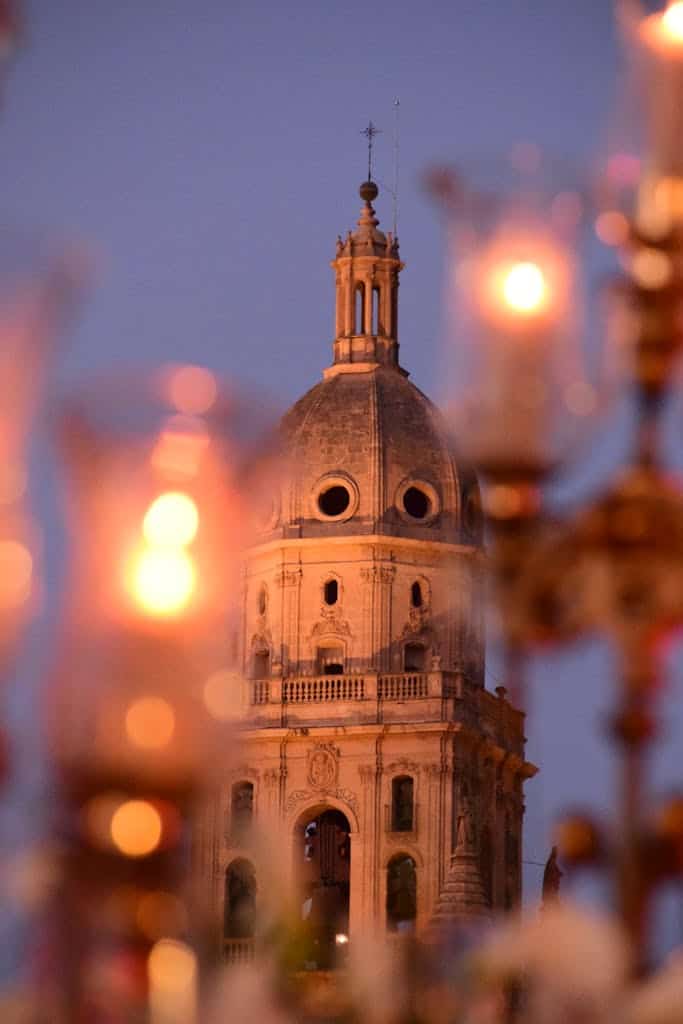Stunning view of Murcia Cathedral's bell tower amidst glowing lights at dusk, capturing serene architecture.
