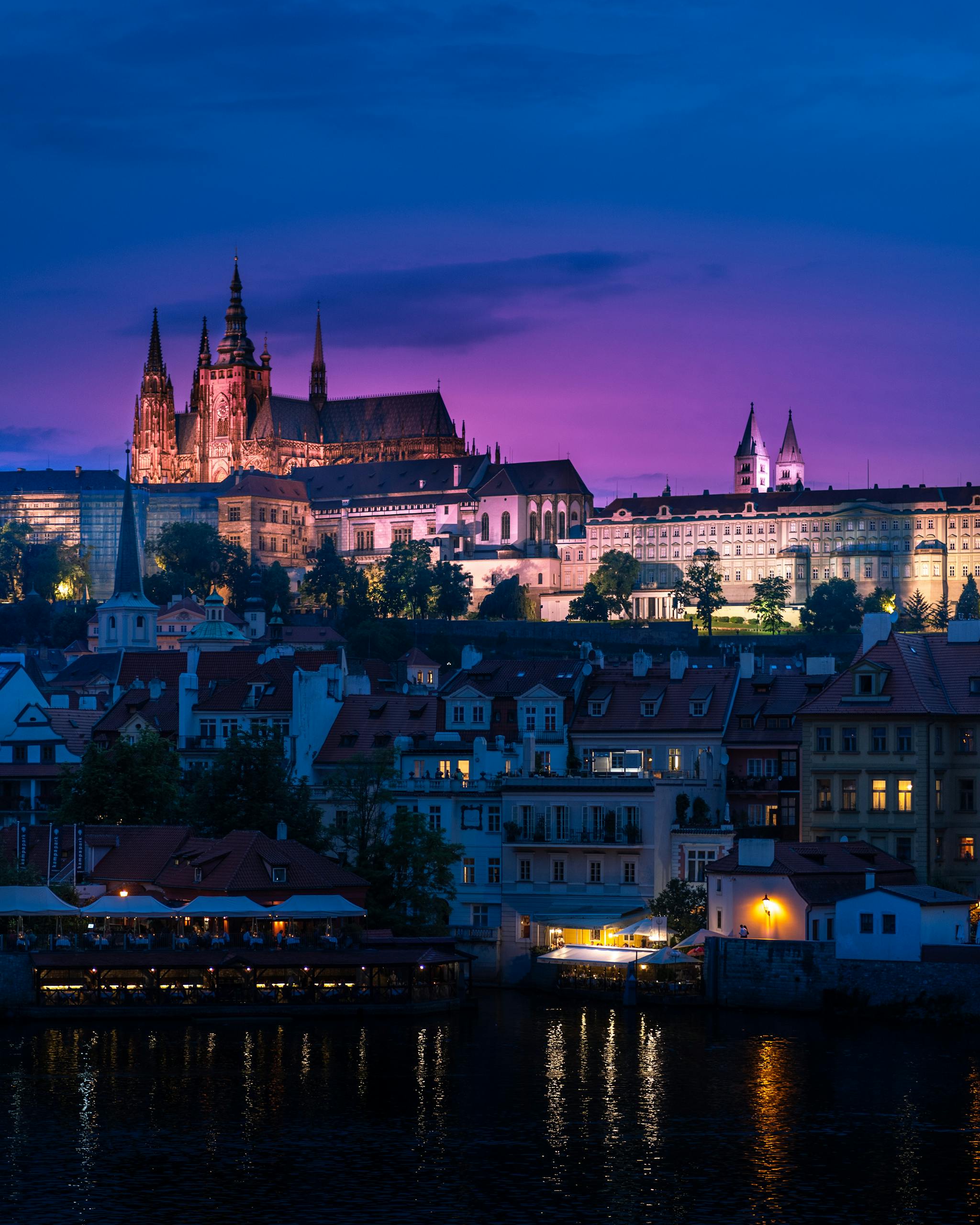 Twilight view of Prague Castle reflected in the Vltava River, showcasing a scenic Czechia cityscape.
