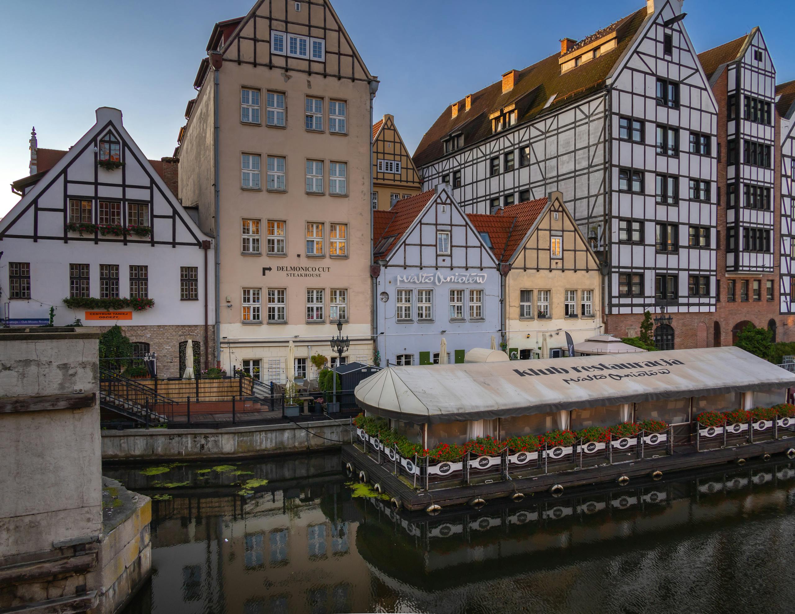 Picturesque view of traditional architecture by the riverside in Gdansk, Poland, featuring historic buildings and calm water reflection.
