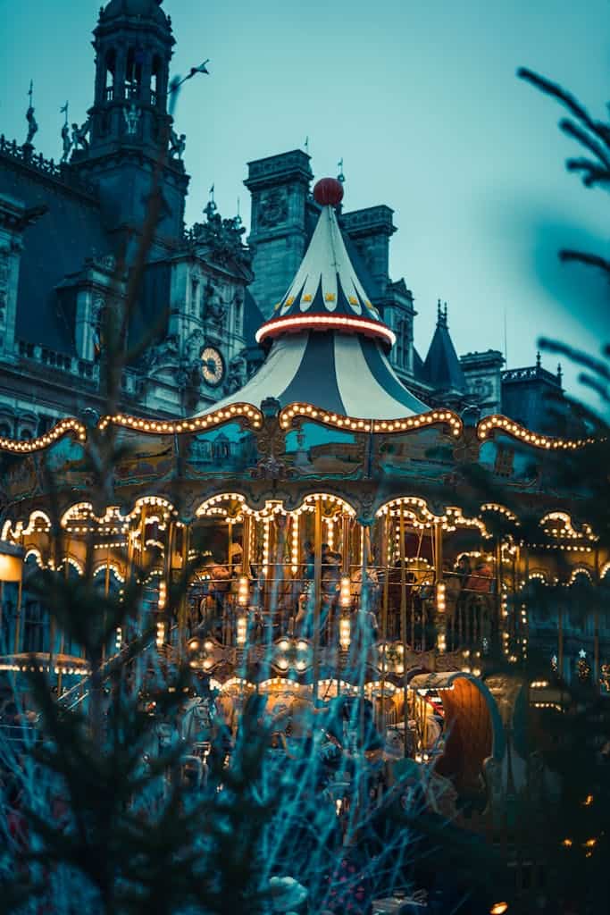A beautifully lit carousel at night in front of historic architecture in Paris, France.