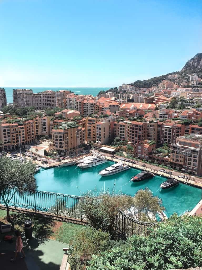 A stunning aerial view of Monte Carlo's vibrant harbor and surrounding cityscape under a clear blue sky.