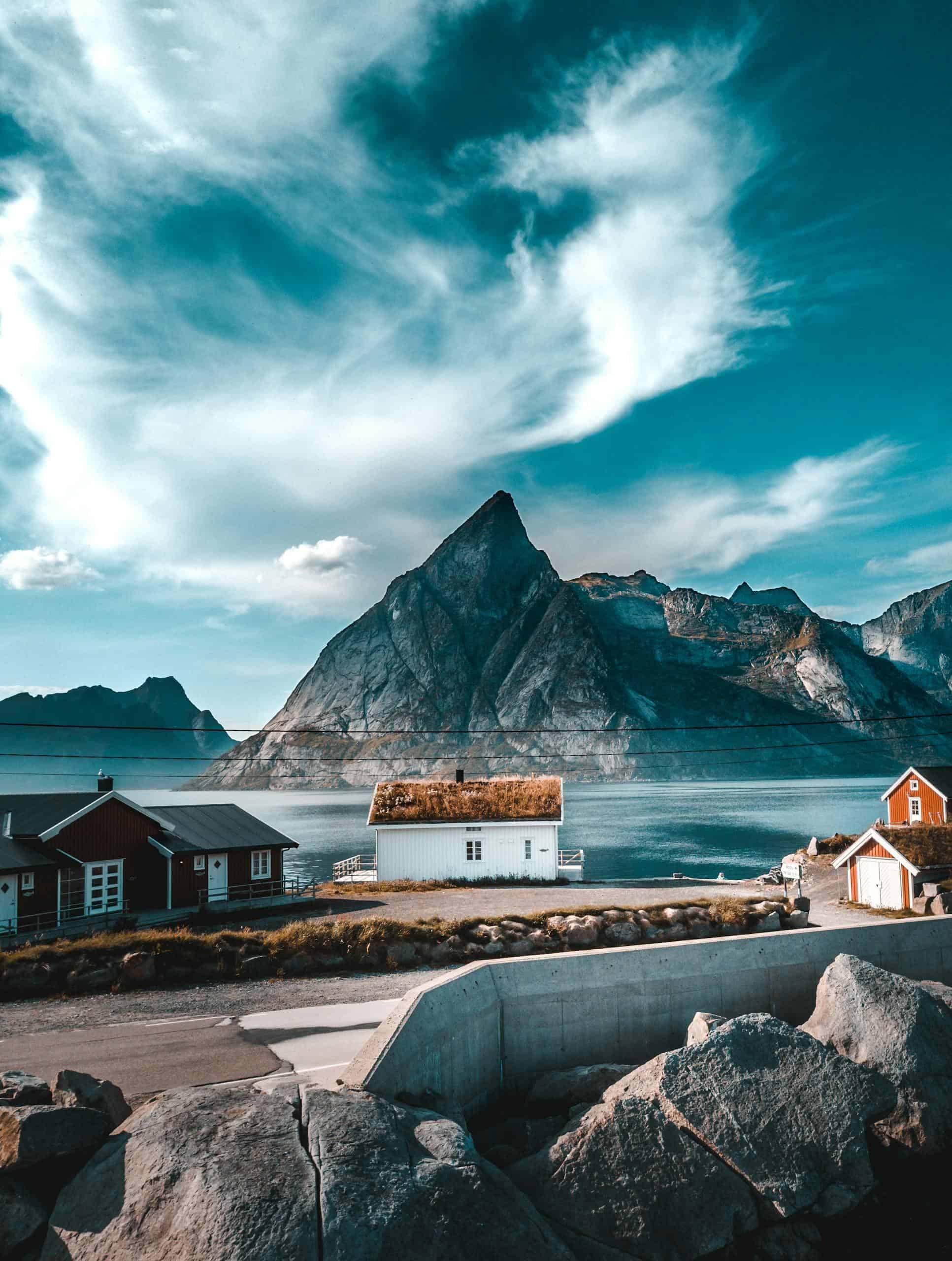Picturesque view of Norwegian village by the sea with mountains and dramatic sky.