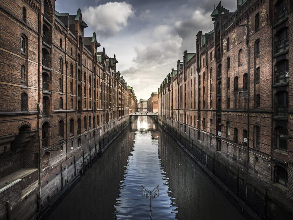 Scenic view of Hamburg's Speicherstadt with brick warehouses and a reflective canal.