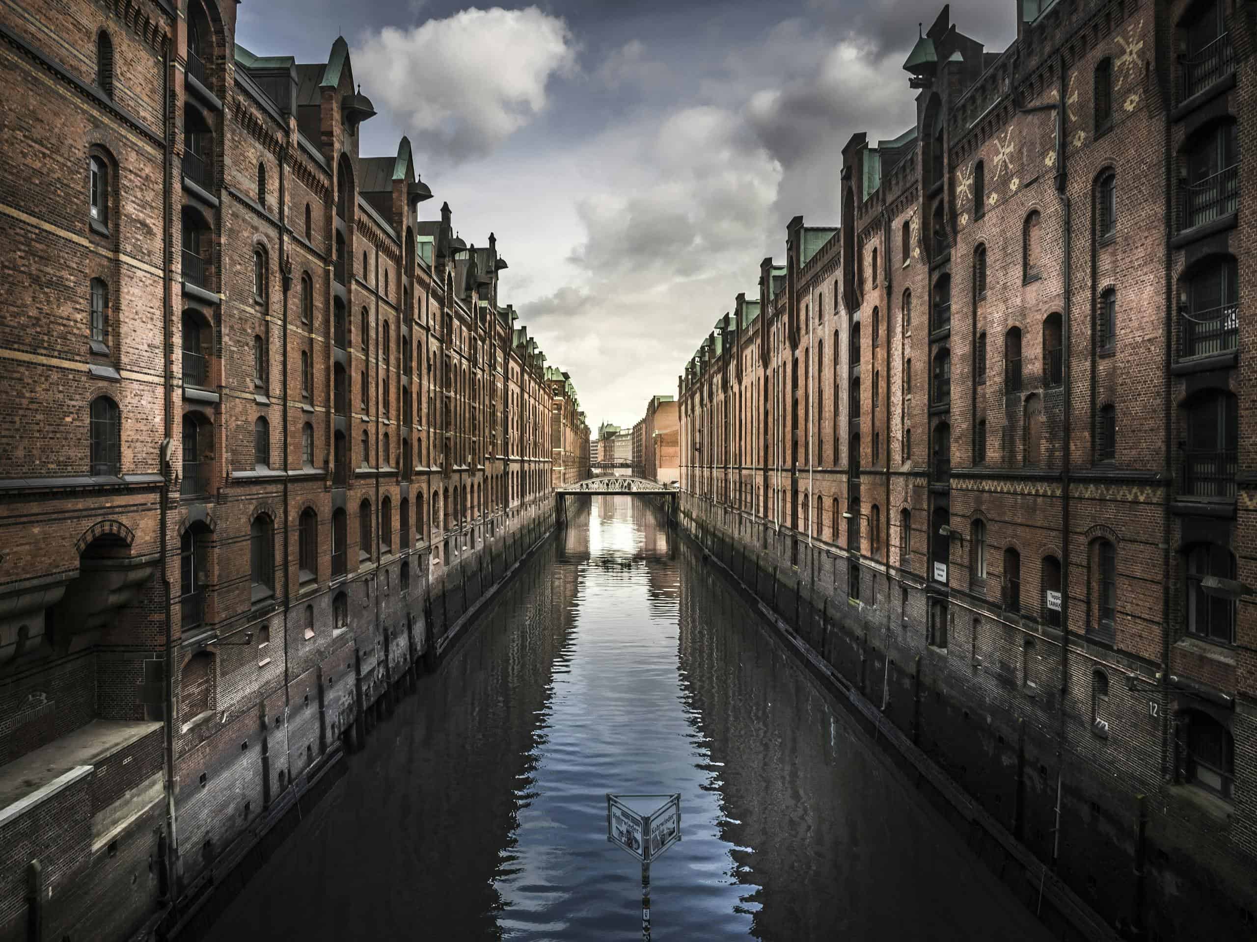 Scenic view of Hamburg's Speicherstadt with brick warehouses and a reflective canal.