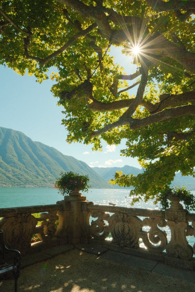 Scenic view of Lake Como from a sun-dappled terrace in Lenno, Lombardy, Italy.