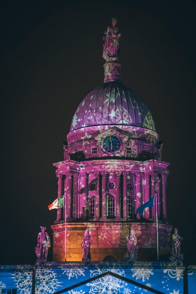 Vibrant night view of Dublin's Custom House adorned with festive lights.