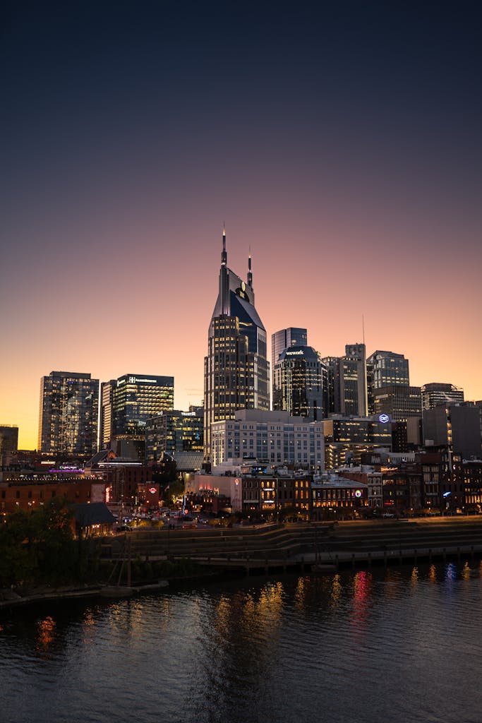 A stunning view of Nashville's skyline at sunset, featuring a calm waterfront reflection.