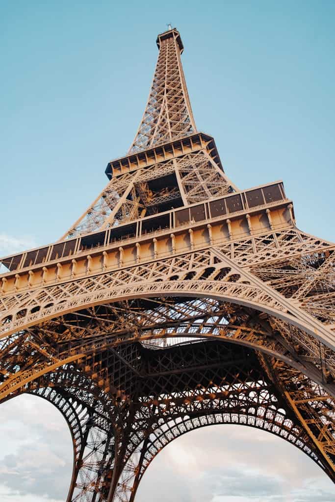 Impressive low angle view of the iconic Eiffel Tower against a clear sky in Paris, France.