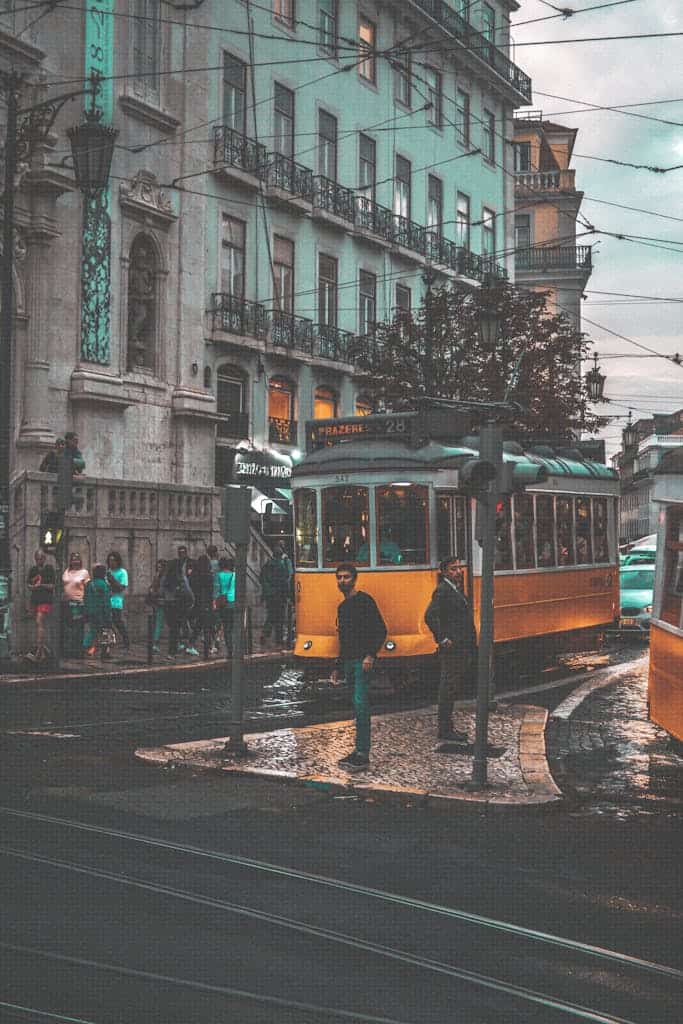 A classic yellow tram navigating through the streets of Lisbon, Portugal, showcasing urban transportation. A walking tour is one of the best things to do for free in Lisbon