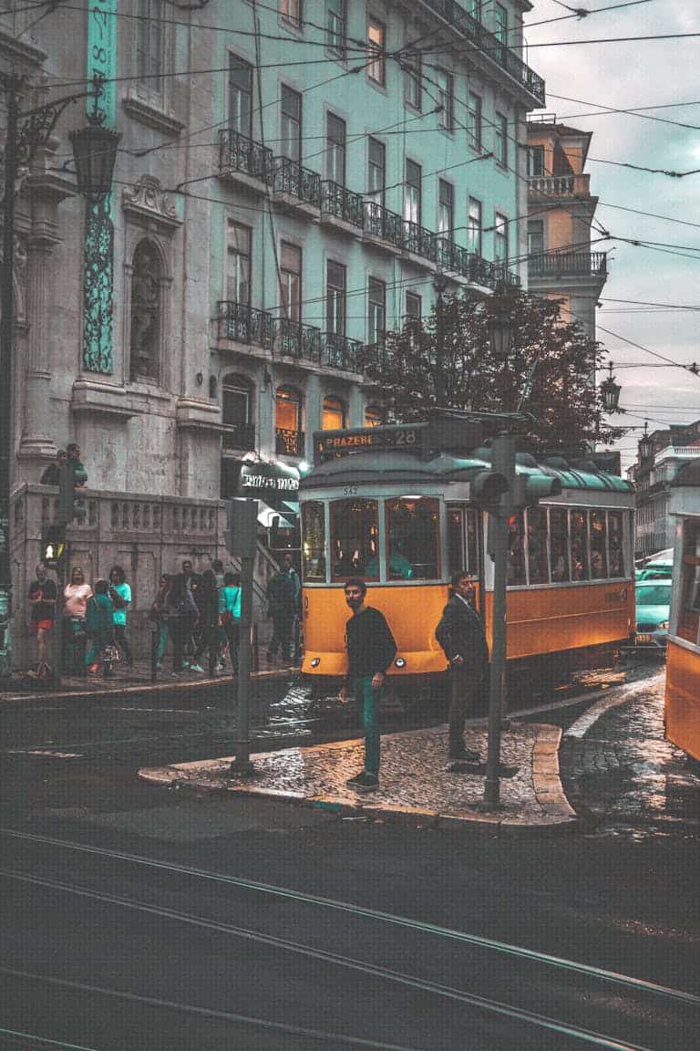 A classic yellow tram navigating through the streets of Lisbon, Portugal, showcasing urban transportation.