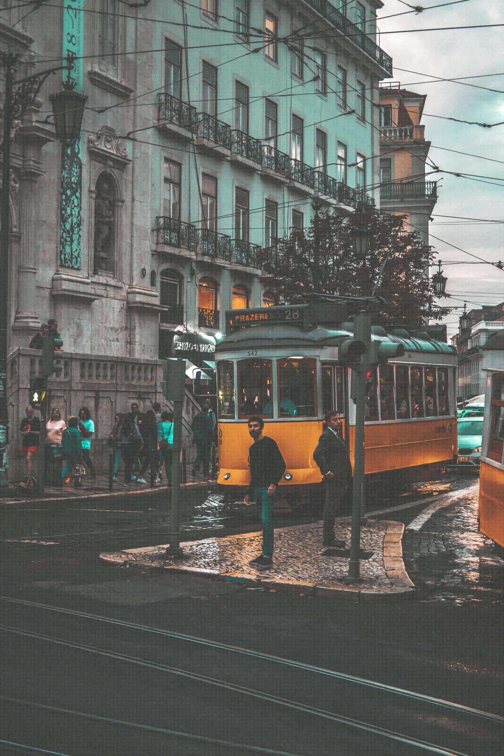 A classic yellow tram navigating through the streets of Lisbon, Portugal, showcasing urban transportation.