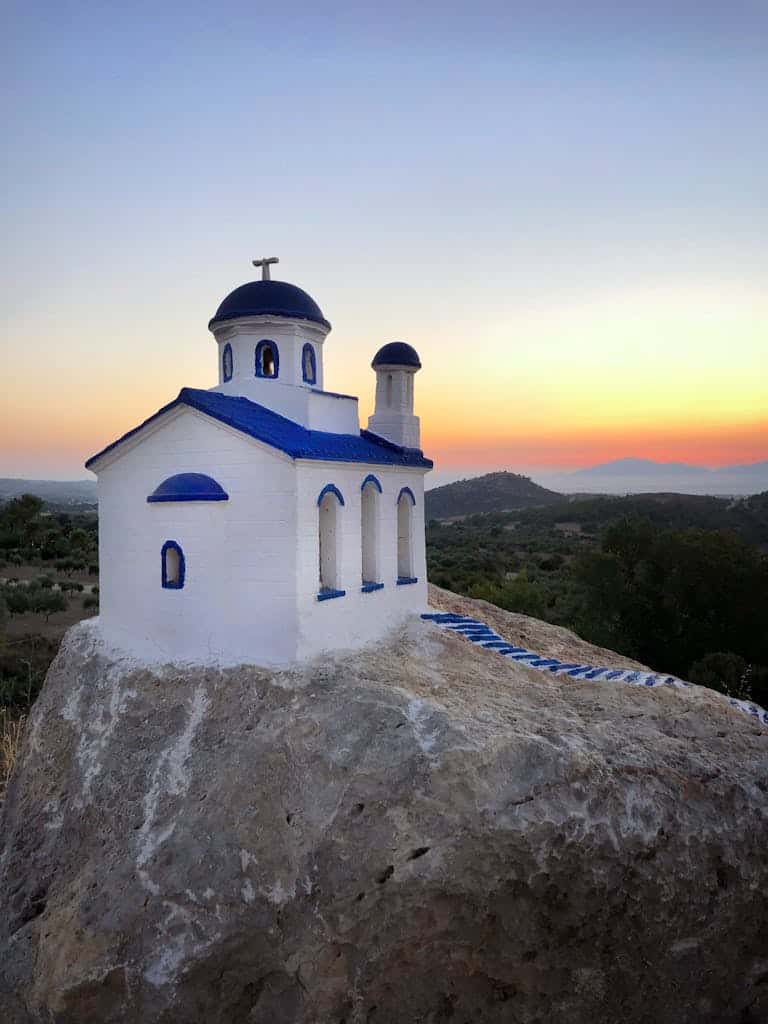 Small white and blue chapel on a rock at sunrise on Kos Island, Greece.