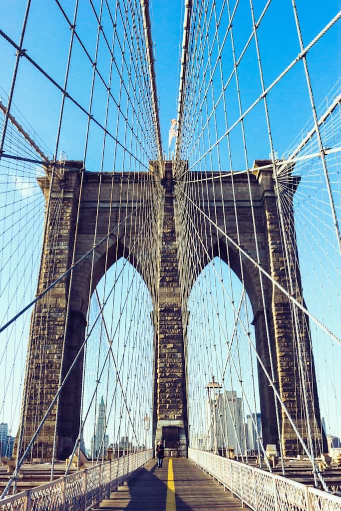 View of the iconic Brooklyn Bridge showcasing its architecture under a clear blue sky in New York City.