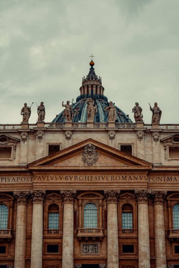 Close-up of St. Peter's Basilica dome with statues, showcasing Vatican's architectural beauty.