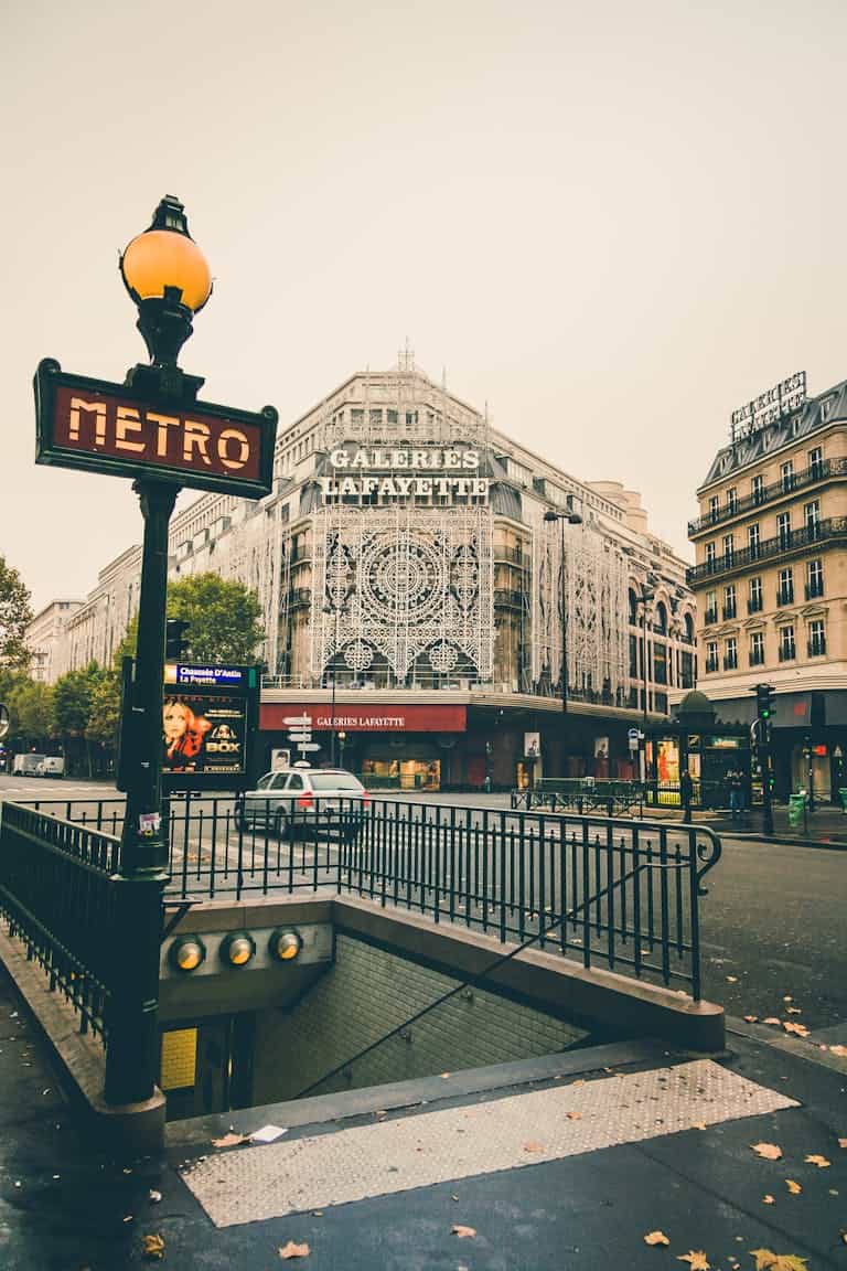 Discover the iconic Galeries Lafayette facade in Paris with nearby metro signs on an overcast day.