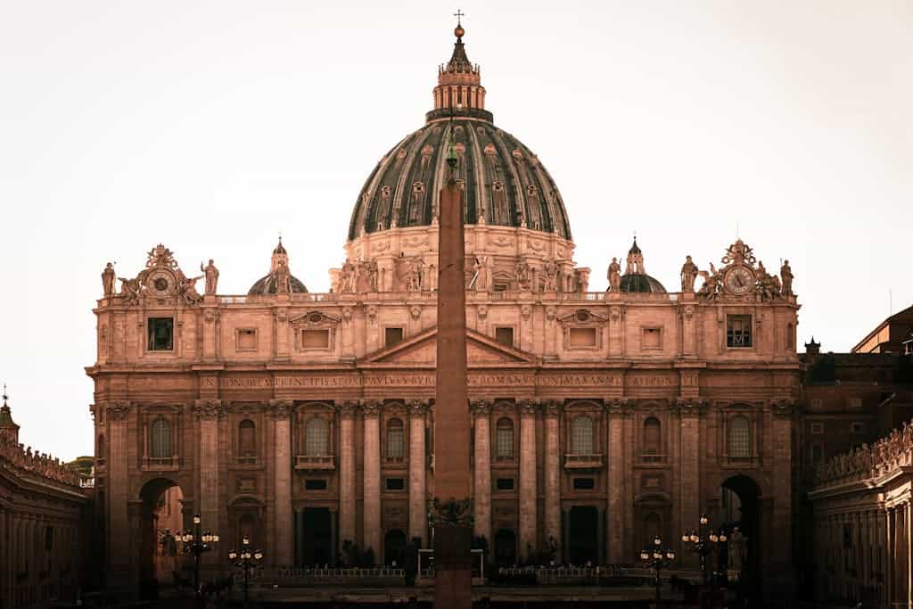 Iconic view of St. Peter's Basilica with the central obelisk, Vatican City under warm light.