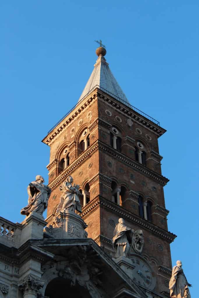 Majestic view of a historic church tower and statues under a clear blue sky.
