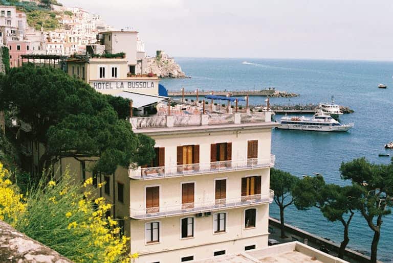 Scenic view of Conca dei Marini with boats, hotel, and coastline in Campania, Italy.