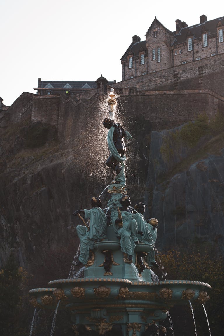 View of the iconic Ross Fountain against Edinburgh Castle in Scotland, highlighting architectural beauty.