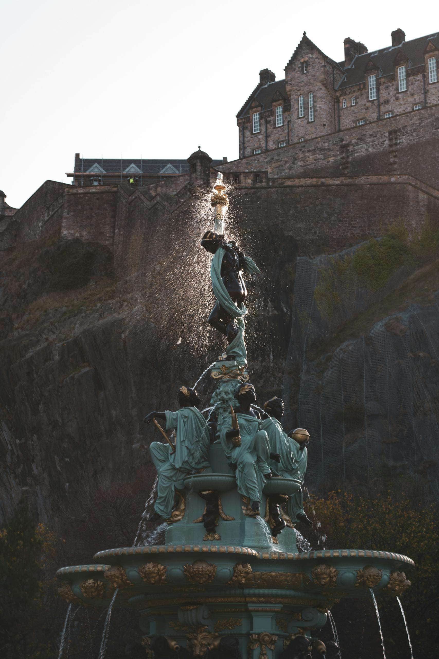 View of the iconic Ross Fountain against Edinburgh Castle in Scotland, highlighting architectural beauty.