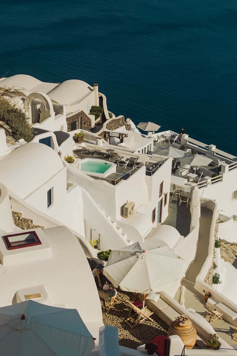 A scenic aerial view of iconic white architecture in Santorini, Greece against blue waters.